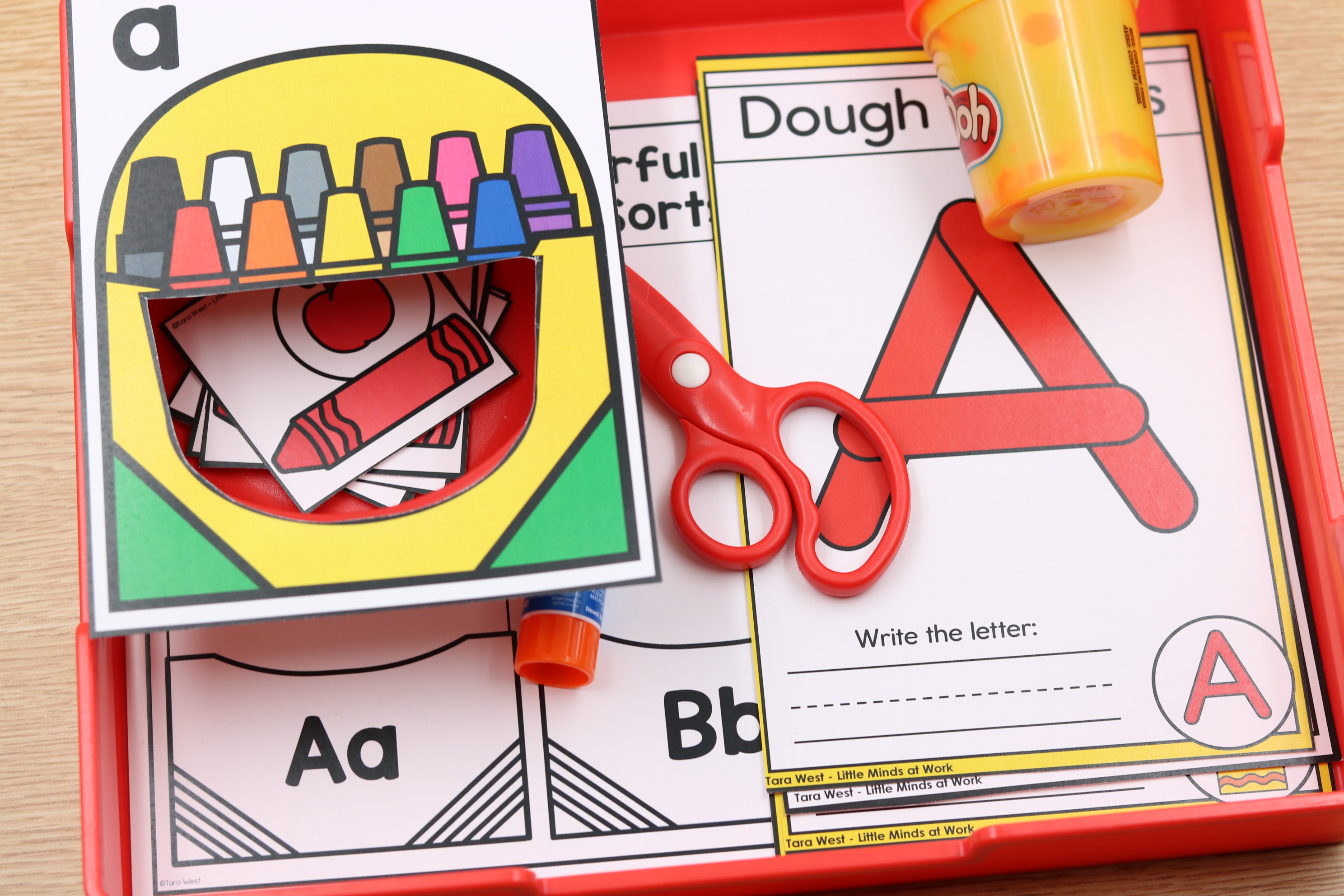 Back-to-school alphabet center featuring letter A activities with a crayon sorting box, letter formation mat, play dough, scissors, and alphabet practice cards.