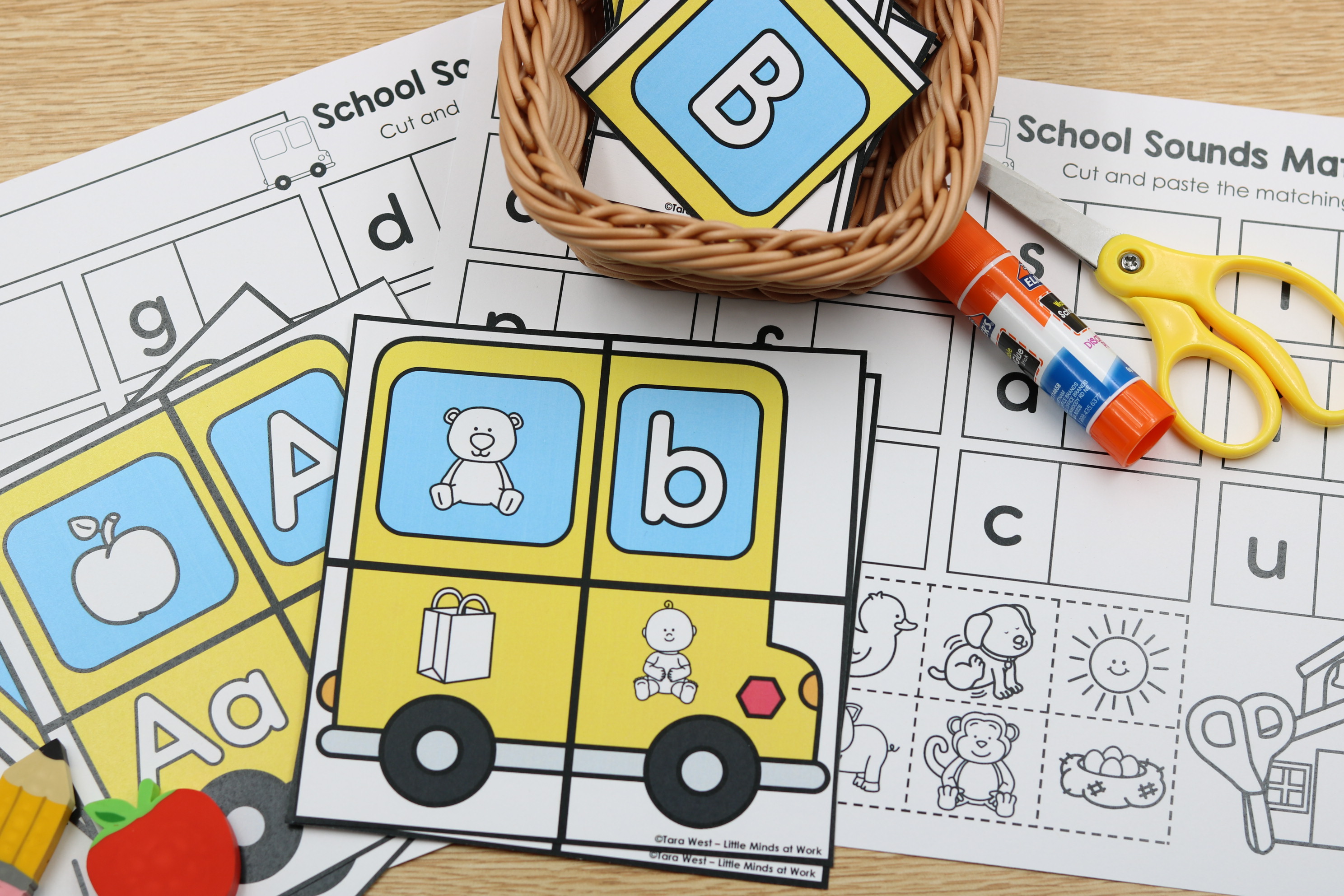 Back-to-school School Sounds Match alphabet center featuring school bus letter and picture cards, beginning sound matching worksheets, scissors, and glue for phonics practice.
