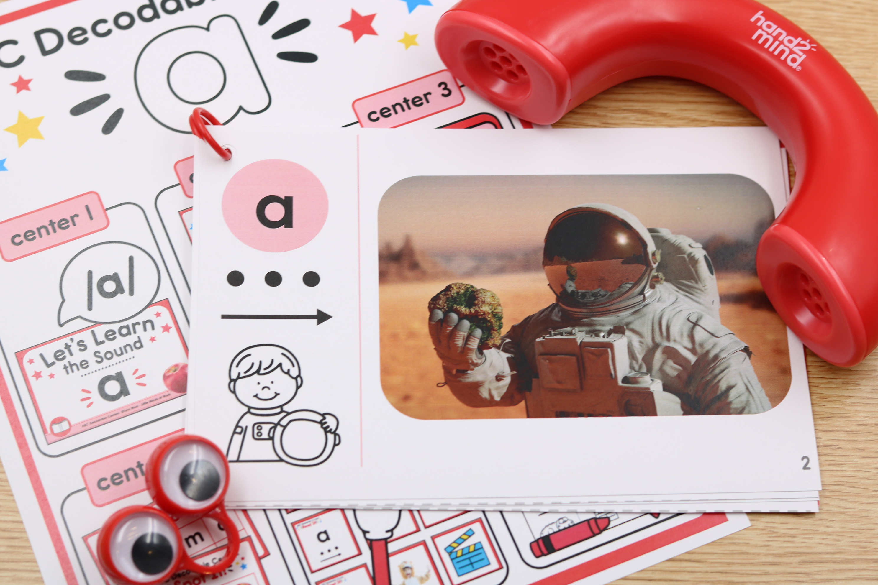 ABC decodable phonics center for letter A featuring a sound card with an astronaut picture, letter-sound practice materials, and a classroom listening phone.