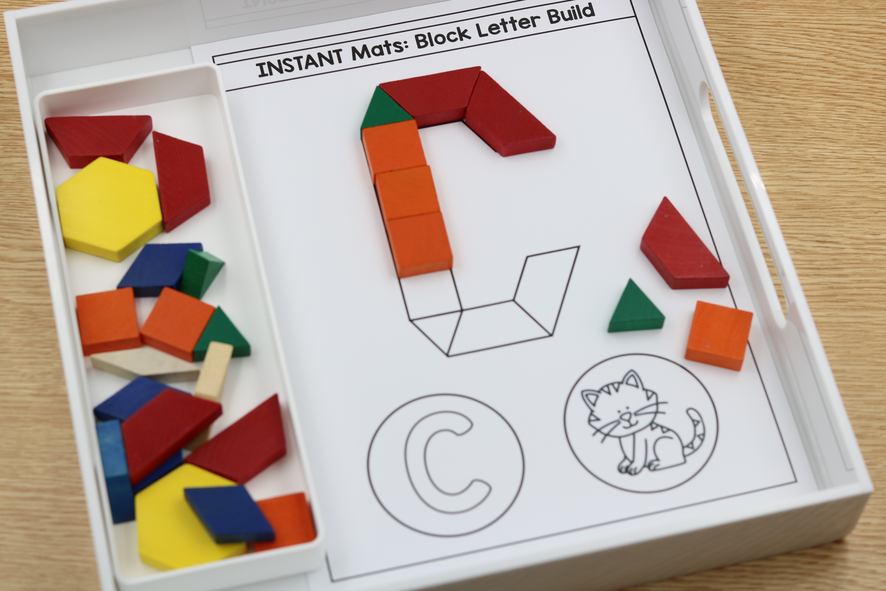 Alphabet fine motor center featuring a letter C block-building mat with colorful pattern blocks and a cat picture for beginning sound practice.