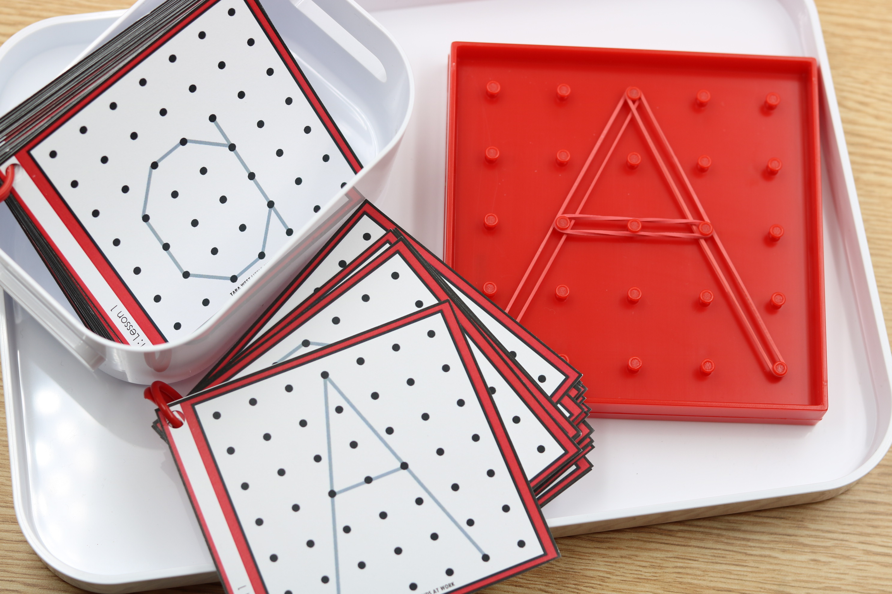 Alphabet fine motor center featuring geoboard letter formation cards and rubber bands for hands-on uppercase letter practice.