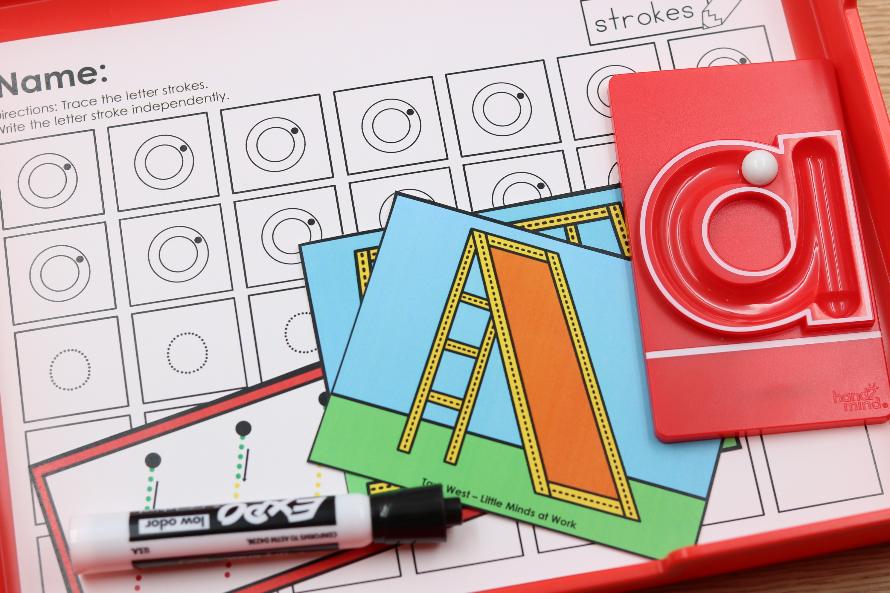 Alphabet fine motor center featuring letter stroke practice with a tracing worksheet, handwriting cards, dry erase marker, and a hands-on letter formation tool.