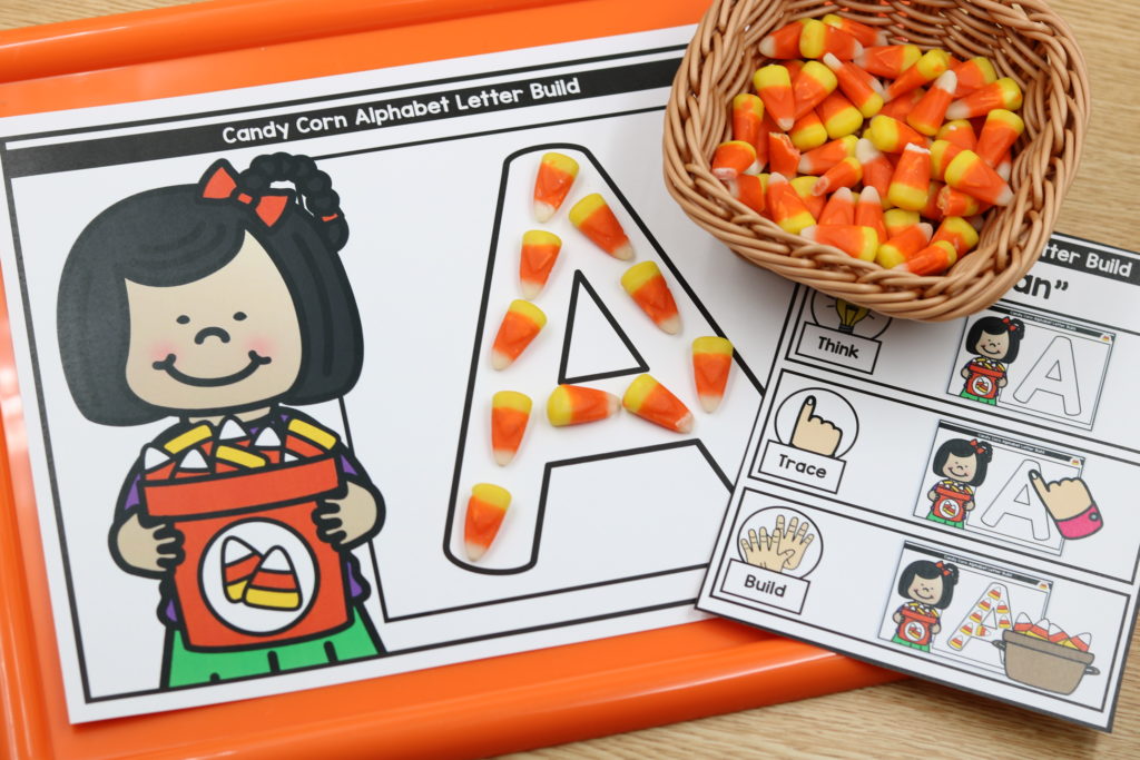 Student building letters with candy corn on October pumpkin fine motor mats